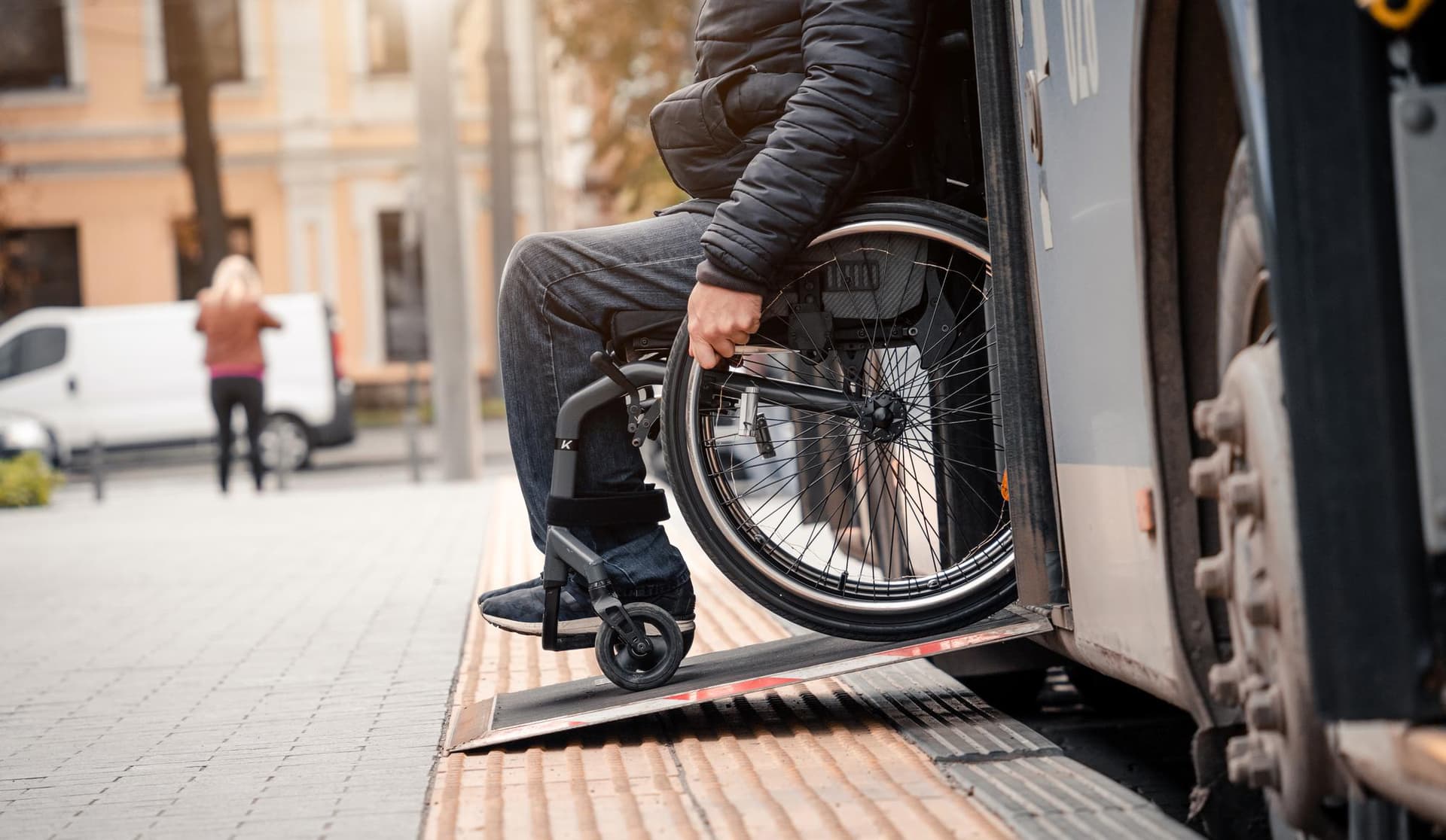 Egy kerekesszékes személy buszra száll egy rámpa segítségével, ami az akadálymentesítés fontosságát hangsúlyozza.